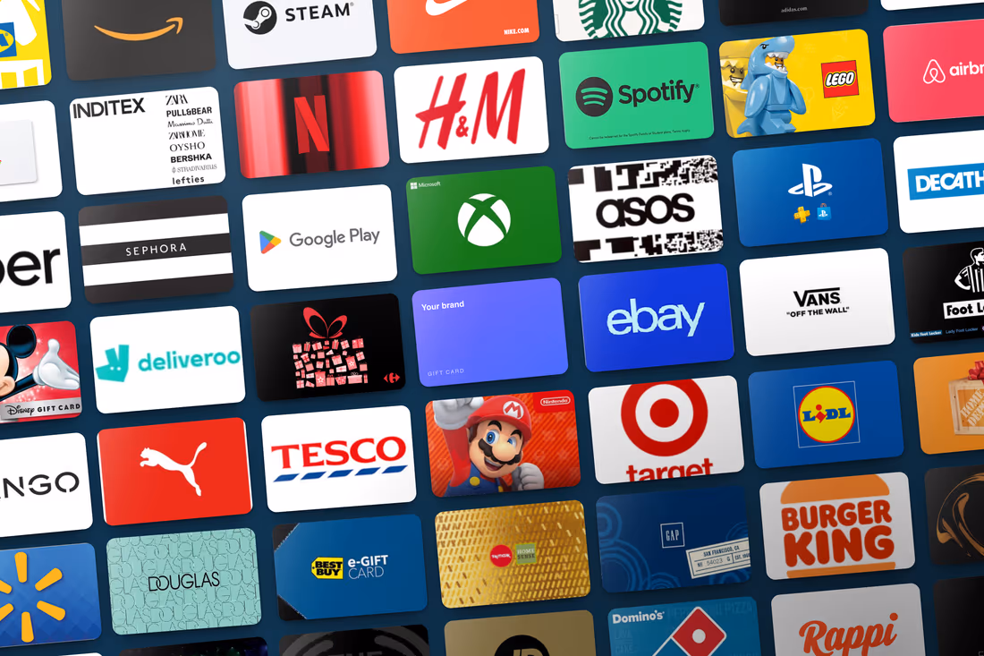 A tilted grid of forty-eight different gift cards - Amazon, Nike, Netflix, H&M, Spotify, LEGO, Xbox, PlayStation, Tesco, Target, Burger King and more - running off every edge of the frame, with one plain violet card reading Your brand sitting among them