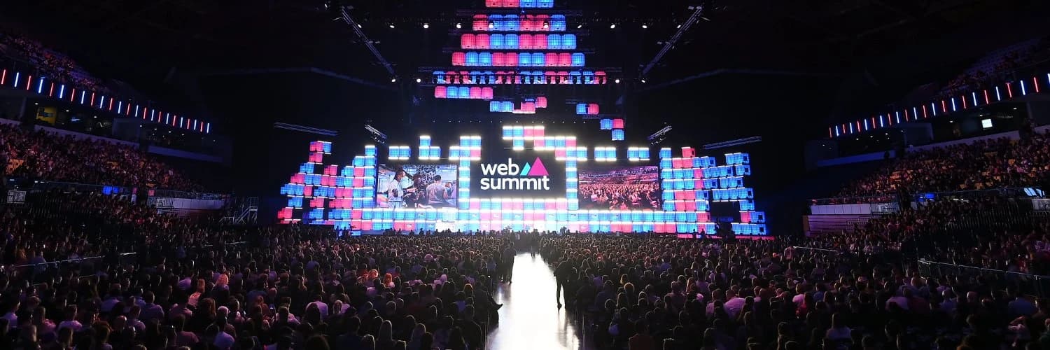 Web Summit Centre Stage in Lisbon, lit in pink and blue in front of a full arena
